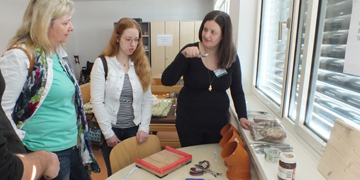 Schülerin erklärt Besucherinnen Verwendung der Esshilfen